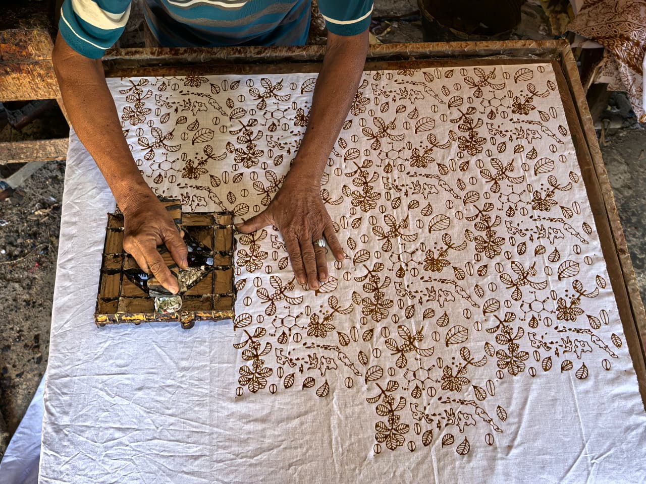 Artisan membuat batik cap tjap tradisional bermotif kopi