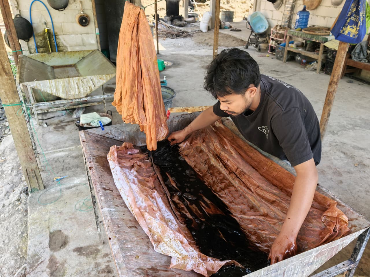 Pencelupan kain batik dalam vat pewarna cokelat kopi