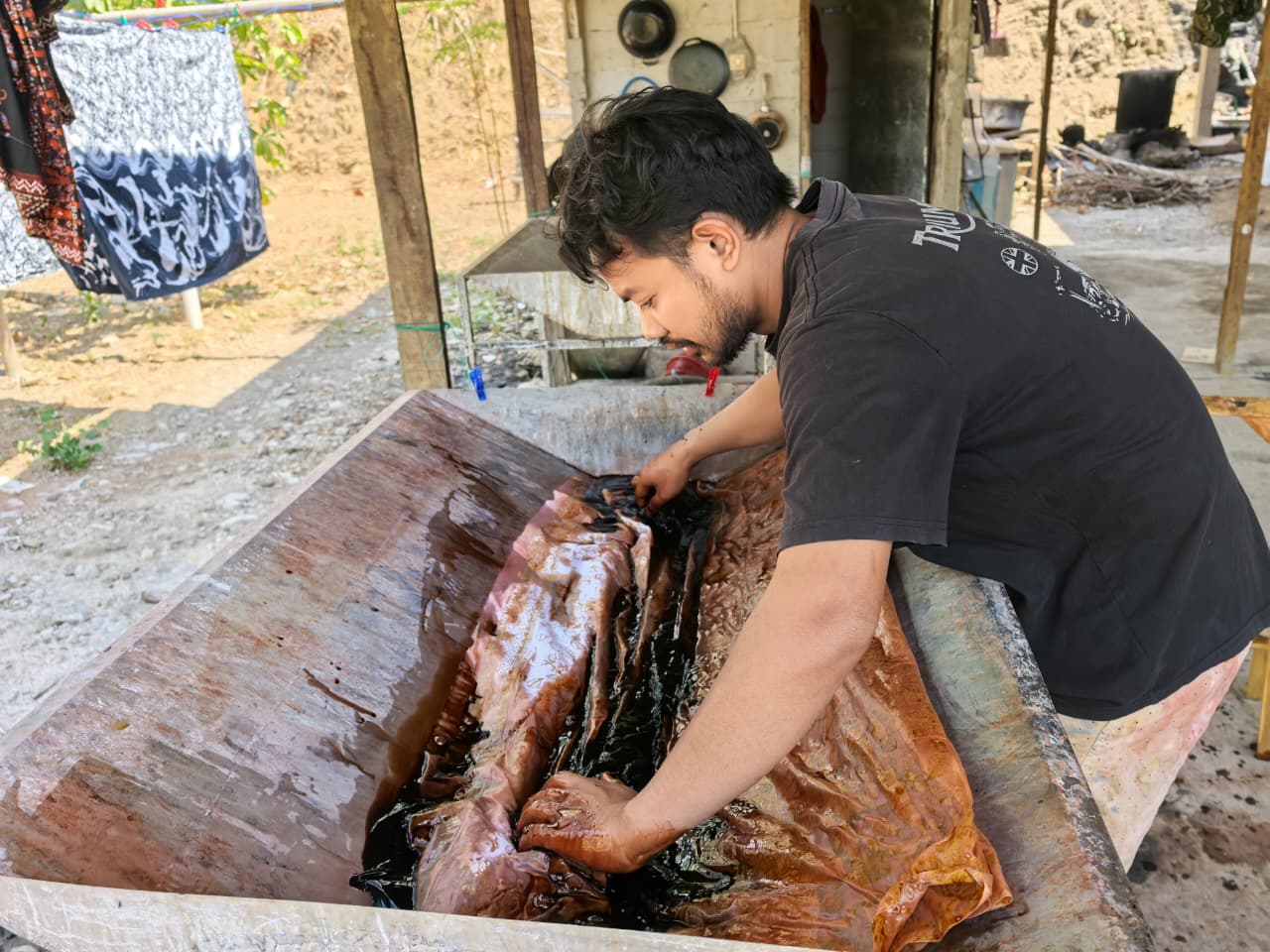 Pencelupan kain batik dalam bak kayu pewarna kopi