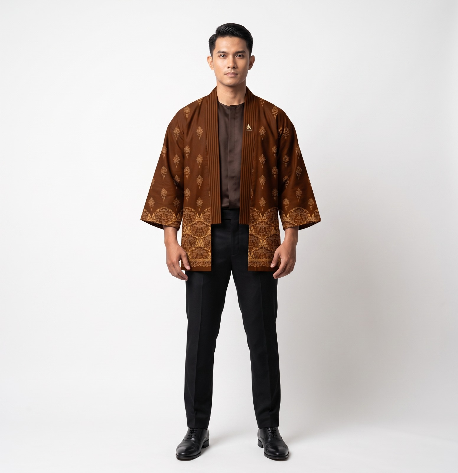 Model mengenakan batik kopi robe satin cokelat dengan motif tradisional, celana formal hitam, dan sepatu oxford